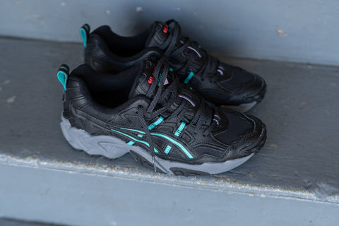 black asics with teal and grey accents on a set of stairs